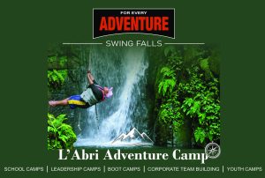 Camp participant leaping off a rope swing into the waterfall plunge pool at Swing Falls